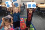 Students shown with a paper with shapes during Play Learn Groups.